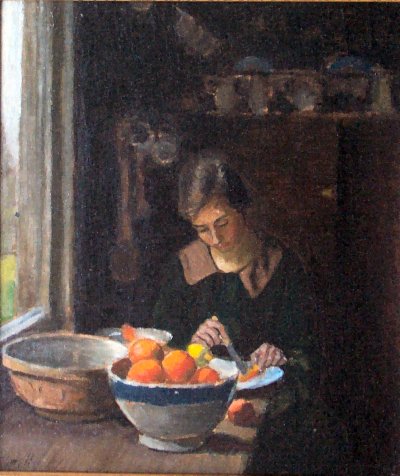 Portrait of a young woman cutting oranges taken from a blue rimmed stoneware bowl